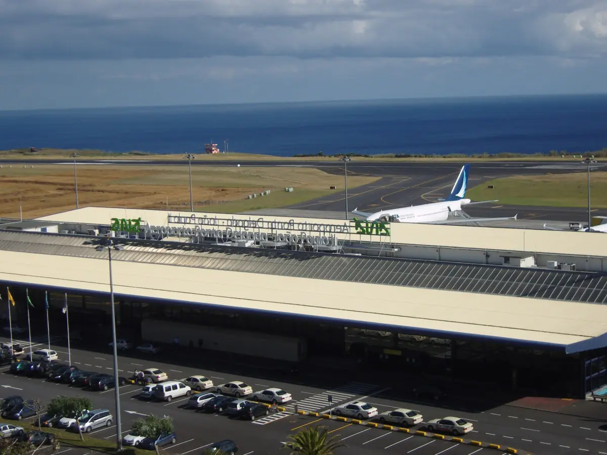 Ponta Delgada airport terminal with parked cars and an aircraft behind